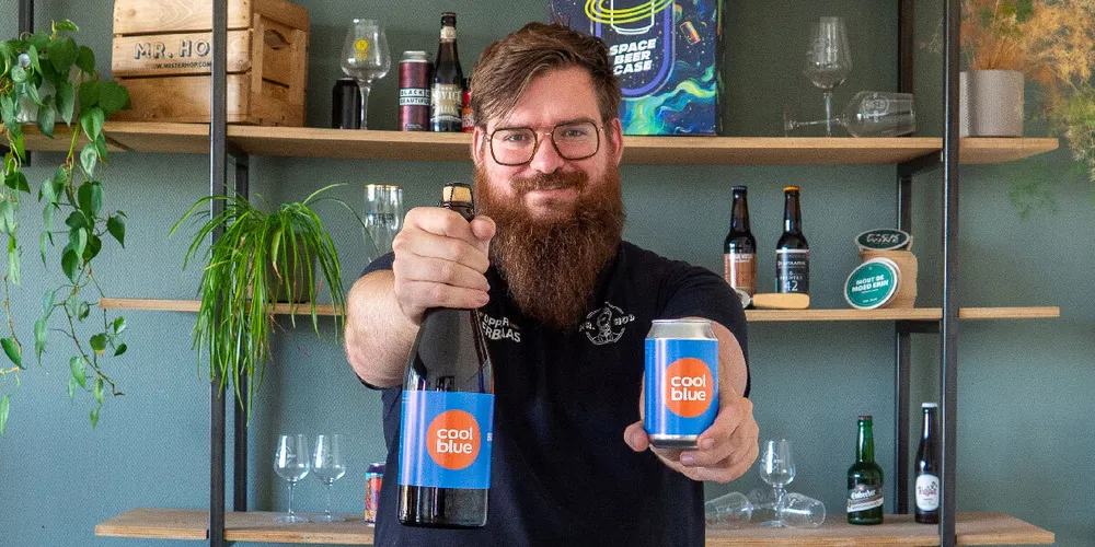Iemand van Mr. Hop houdt een fles en een blik met een eigen etiket omhoog